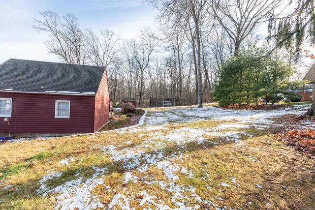 a backyard of a house with trees and covered with snow
