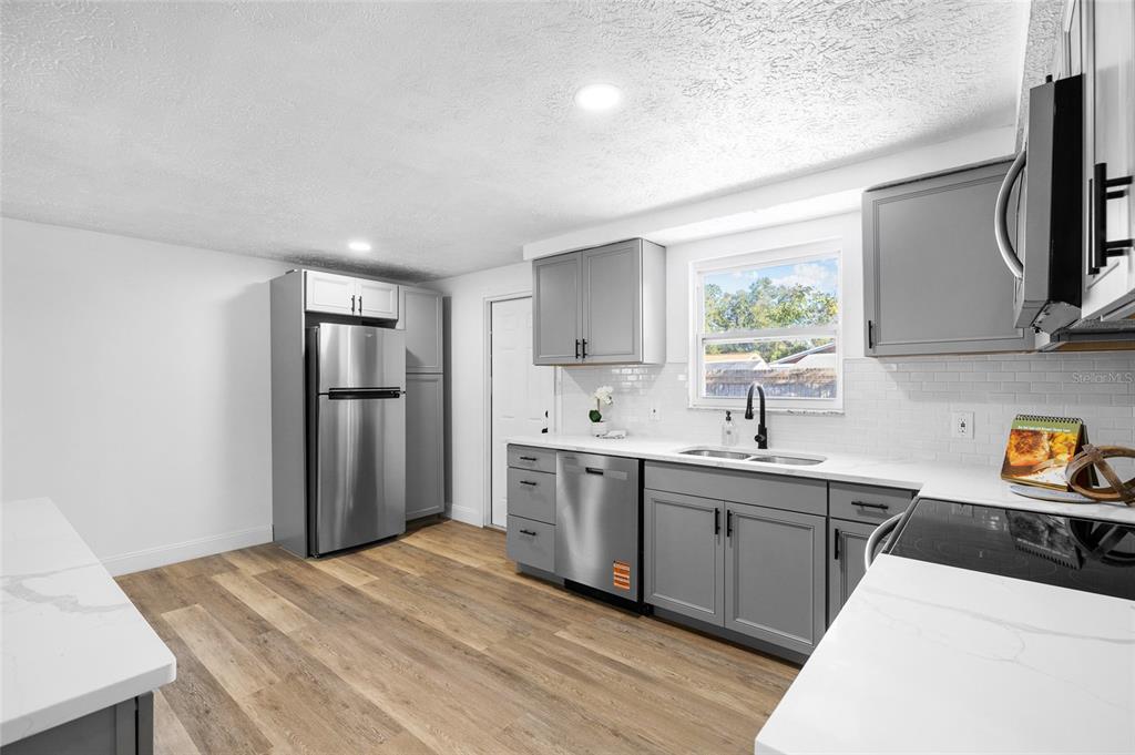 4244 Mesa Drive New Port Richey, FL 34653 - Photo 13 of 35 a kitchen with stainless steel appliances granite countertop a sink stove and refrigerator