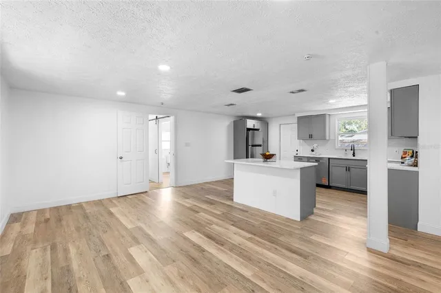 a view of a kitchen with kitchen island a sink wooden floor and a stove top oven