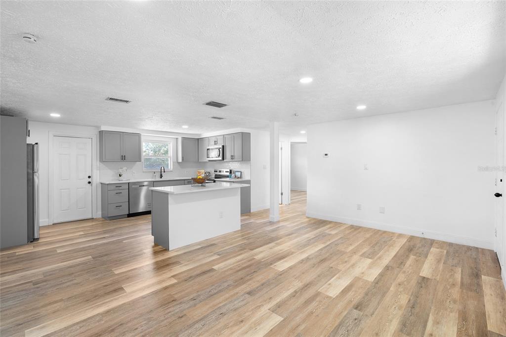 4244 Mesa Drive New Port Richey, FL 34653 - Photo 8 of 35 a large white kitchen with kitchen island a sink white cabinets and stainless steel appliances