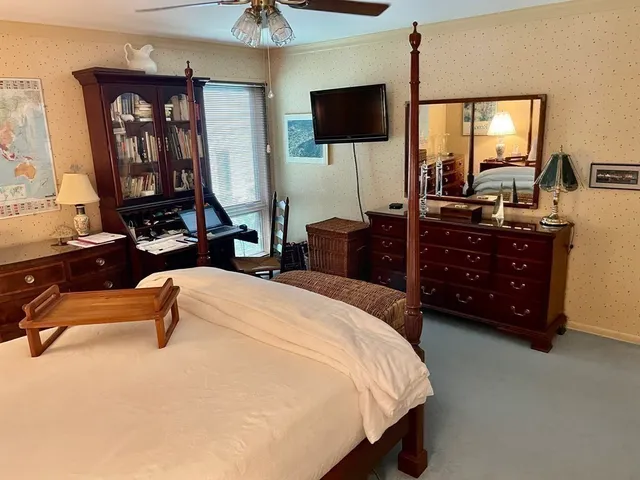 a bedroom with a bed a mirror on dresser and a flat screen tv