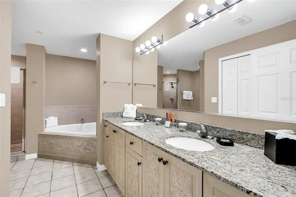 a bathroom with a granite countertop double vanity sink a mirror and a bathtub