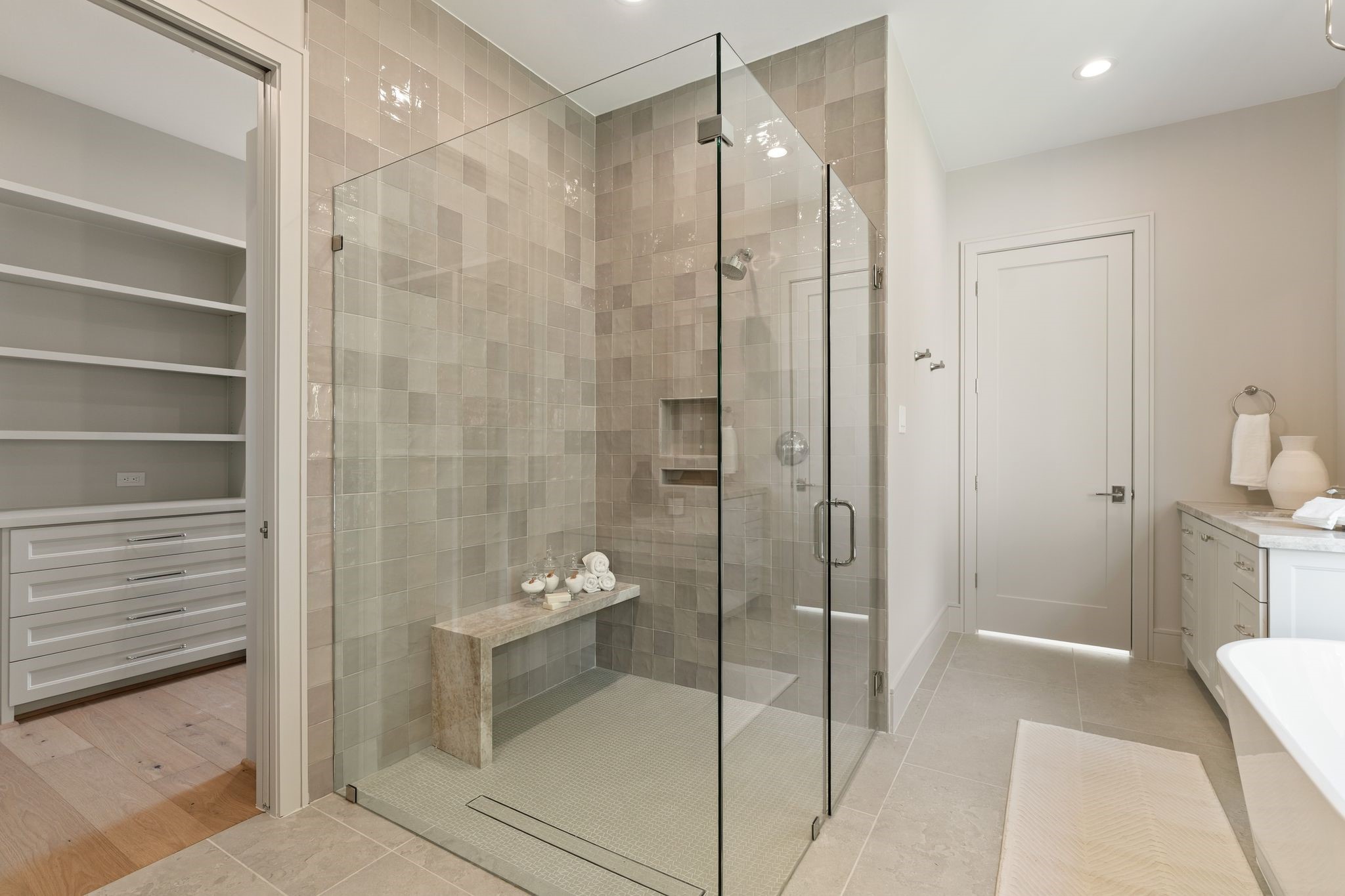 711 East 12th Street Houston, TX 77008 - Photo 32 of 47 Luxurious walk-in shower enclosed in glass, with layered stone-inspired tile, polished fixtures and a built-in bench.