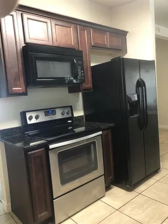 a kitchen with granite countertop a refrigerator stove and microwave