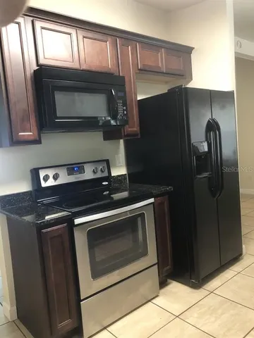 a kitchen with granite countertop a refrigerator stove and microwave