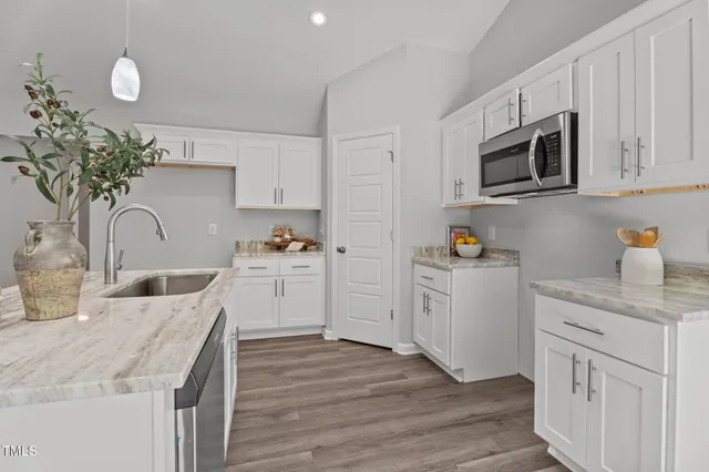 a kitchen with granite countertop white cabinets and stainless steel appliances
