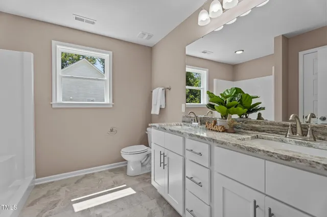 a bathroom with a granite countertop sink mirror vanity and toilet