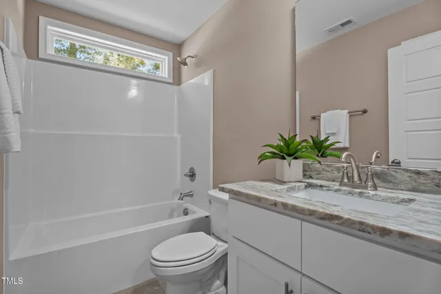 a bathroom with a granite countertop sink a toilet a mirror and shower