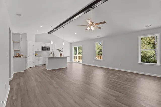 a view of an empty room with window and wooden floor