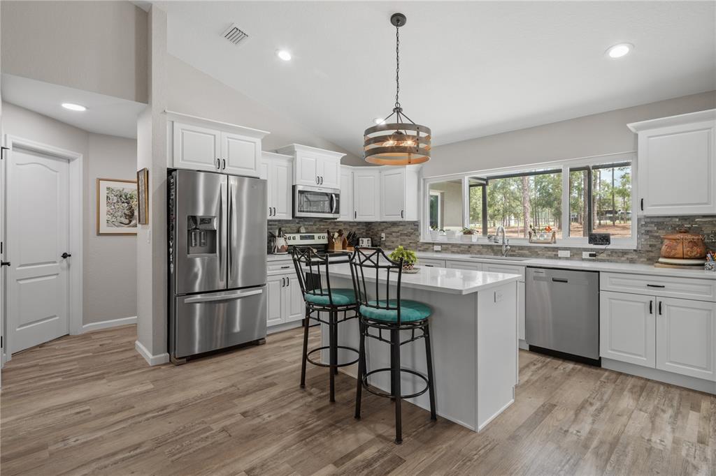 12929 Southwest 89th Street Dunnellon, FL 34432 - Photo 15 of 76 a kitchen with stainless steel appliances a dining table chairs refrigerator and microwave