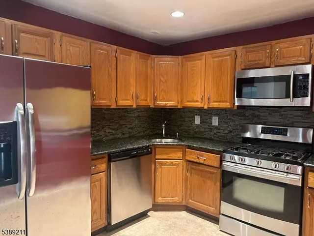 a kitchen with stainless steel appliances granite countertop a stove a sink and a microwave