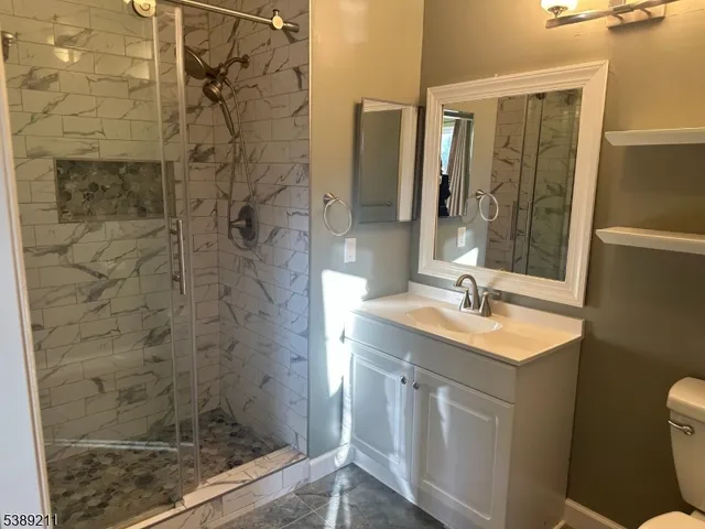 a bathroom with a sink a toilet a mirror and shower