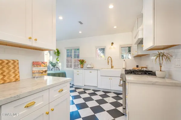 a kitchen with stainless steel appliances granite countertop a sink a stove a chimney a refrigerator and cabinets