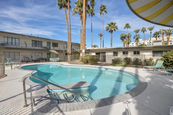 a view of a swimming pool with a lawn chairs under an umbrella