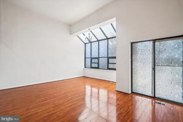 a view of an empty room with window and wooden floor
