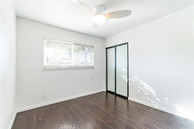 an empty room with wooden floor chandelier fan and windows