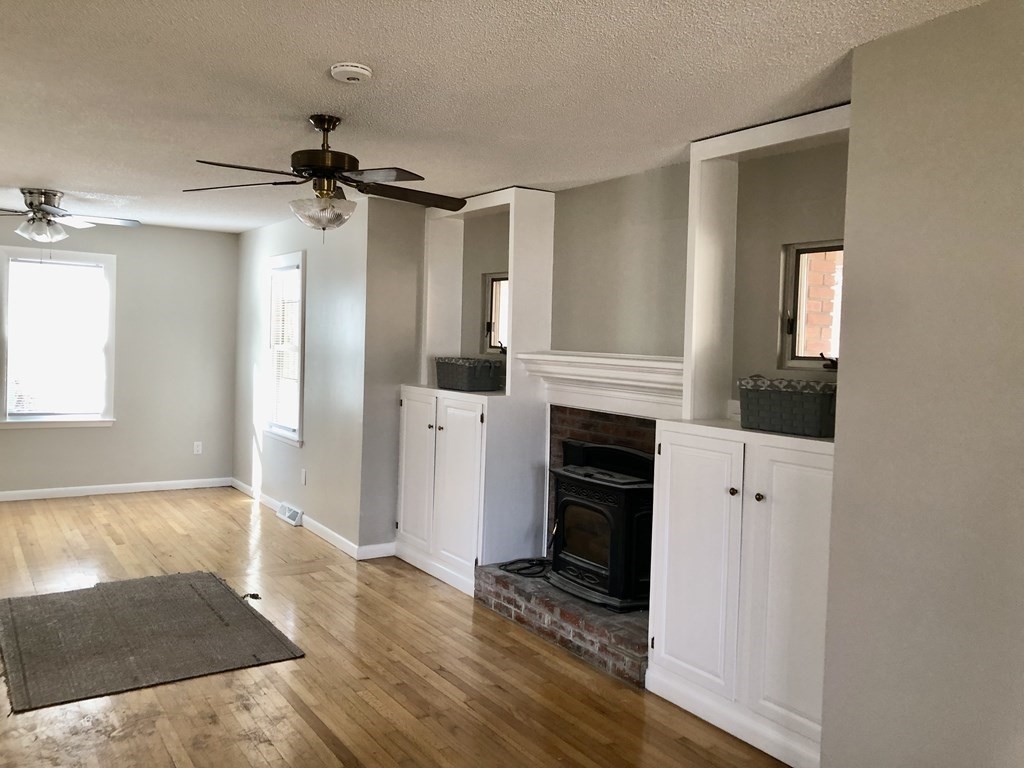 945 Tinkham Road Wilbraham, MA 01095 - Photo 6 of 26 wooden floor in an empty room with a fireplace