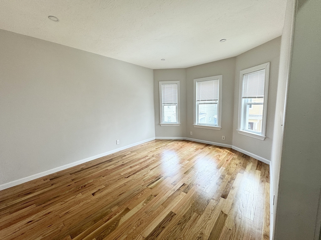6 Cawfield Street, Unit 2 Boston, MA 02125 - Photo 3 of 8 an empty room with wooden floor and windows