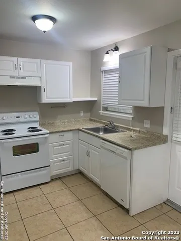 a kitchen with granite countertop white cabinets and white appliances