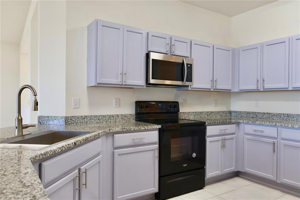 2164 Carriage Pointe Loop Apopka, FL 32712 - Photo 11 of 30 a kitchen with granite countertop white cabinets and stainless steel appliances