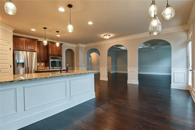 a kitchen with stainless steel appliances granite countertop a refrigerator a stove and a wooden floor