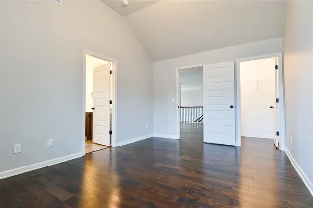 an empty room with wooden floor fireplace and windows