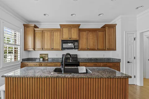 a kitchen with kitchen island granite countertop a sink window and cabinets