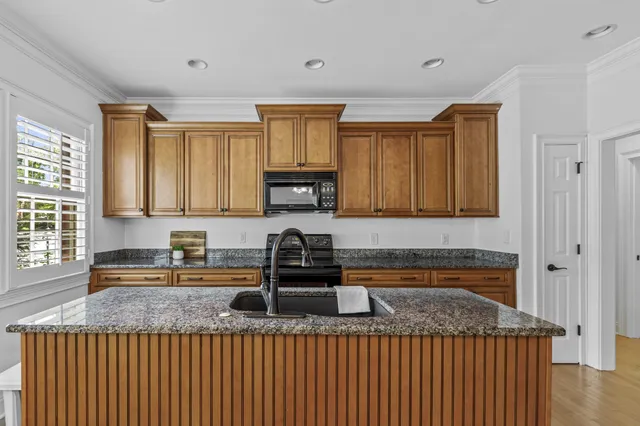 a kitchen with kitchen island granite countertop a sink window and cabinets