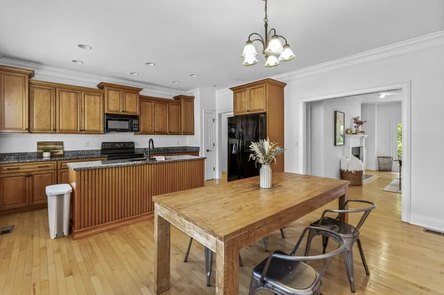 a kitchen with kitchen island granite countertop a stove top oven a sink dishwasher a dining table and chairs with wooden floor