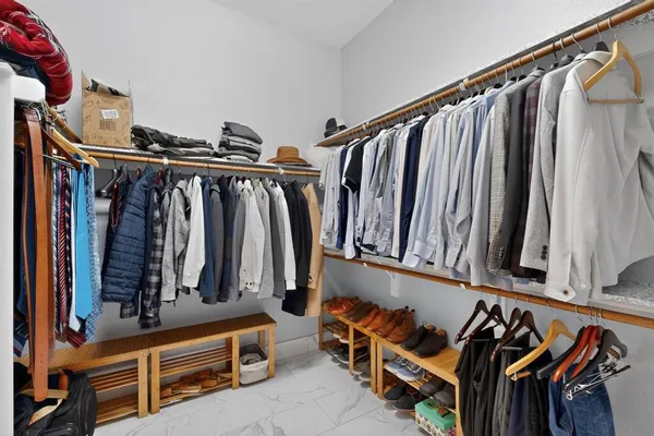 a view of walk in closet with clothes and shoes