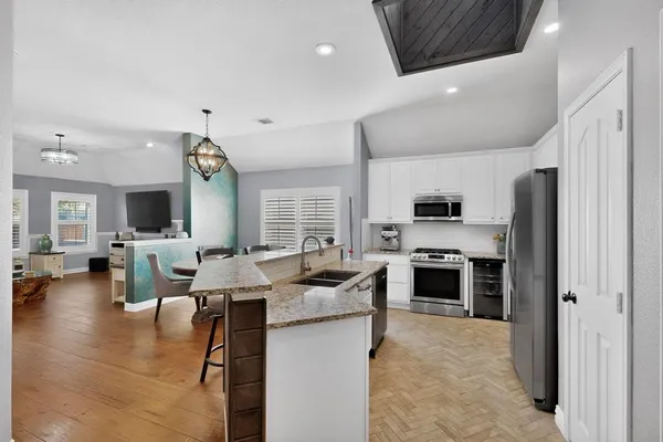 a large kitchen with stainless steel appliances kitchen island granite countertop a refrigerator and stove