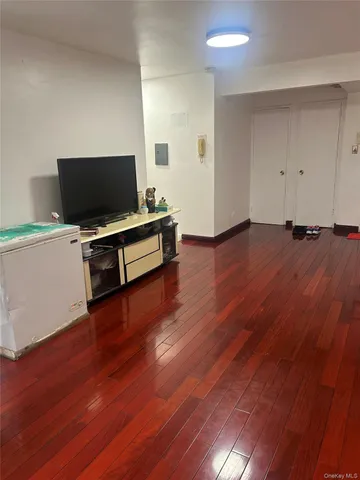 a view of a livingroom with a flat screen tv wooden floor and a window