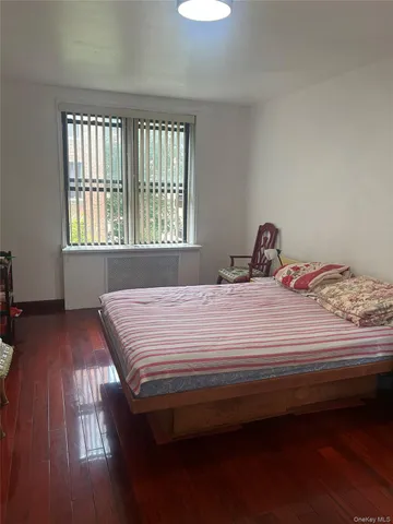 a bedroom with a bed wooden floor and window