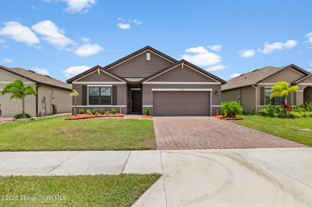 a front view of a house with a garden and plants