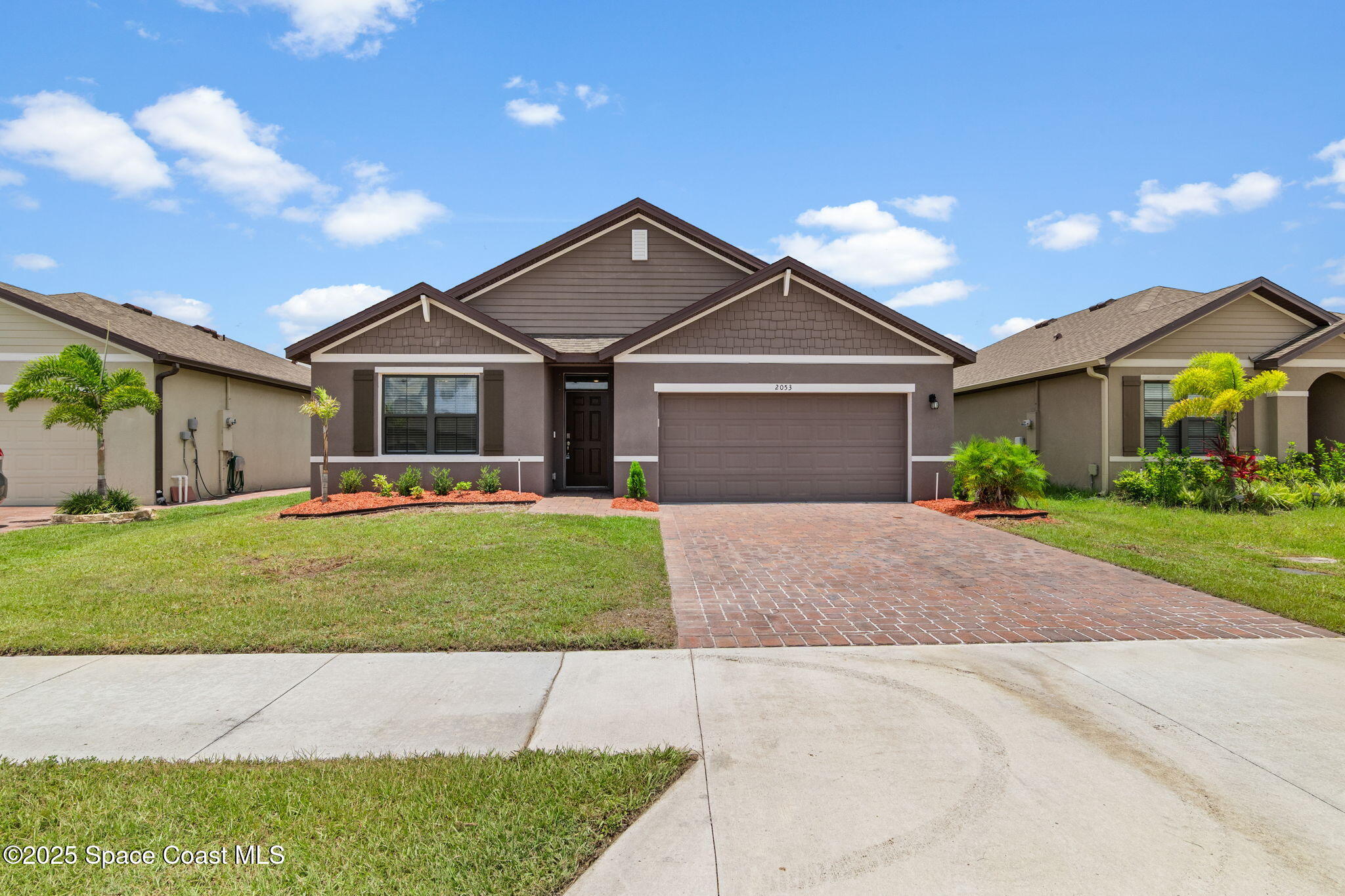 a front view of a house with a garden and plants