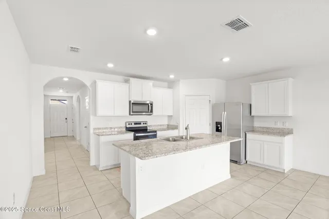 a large kitchen with kitchen island a sink a stove a refrigerator and a cabinets