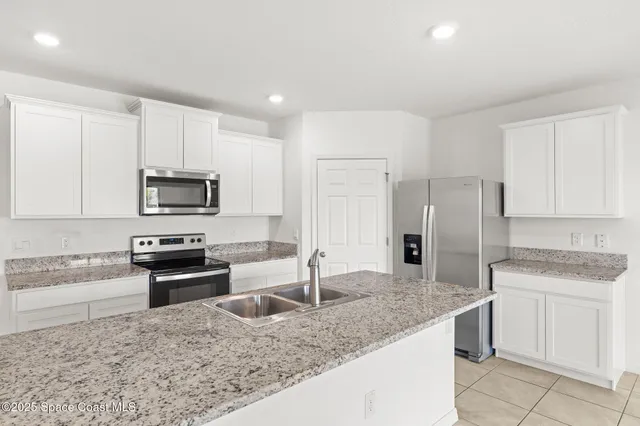 a kitchen with stainless steel appliances granite countertop a sink a stove a microwave and a refrigerator