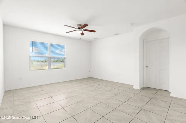 an empty room with windows and ceiling fan