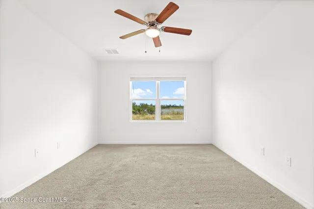 an empty room with a window and a ceiling fan