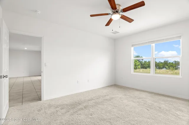 an empty room with a window and a ceiling fan