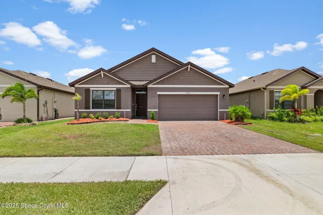 a front view of a house with a garden and plants