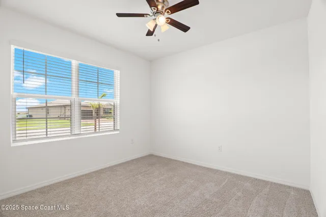 an empty room with a window and a fan