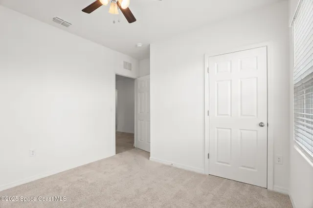 an empty room with ceiling fan and window
