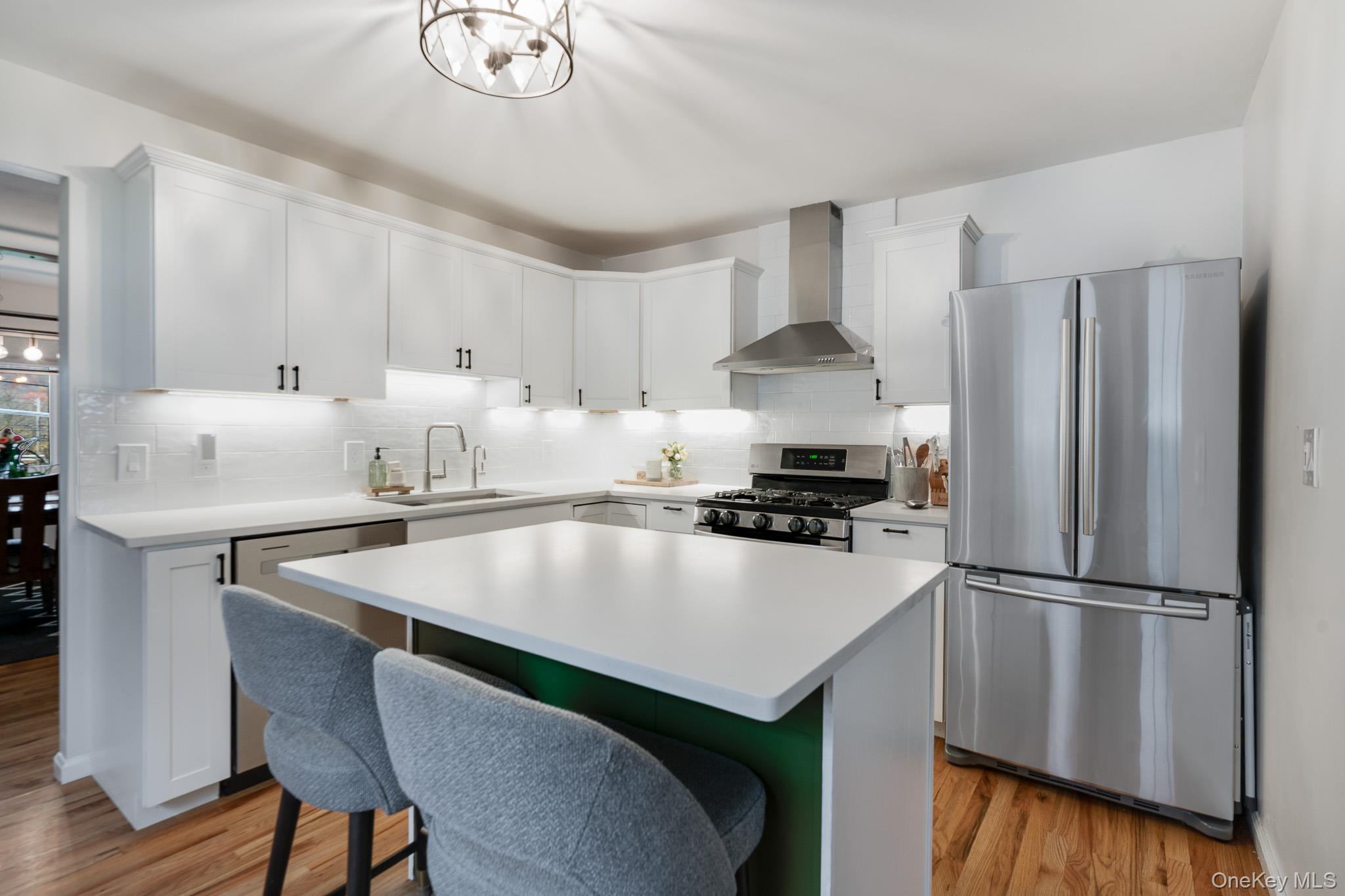 a kitchen with kitchen island a stove a refrigerator and a dining table with wooden floor