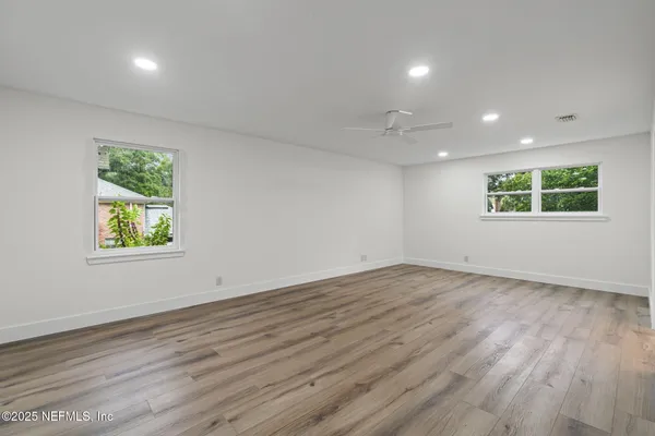an empty room with wooden floor and windows