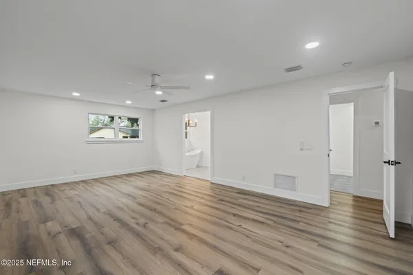 an empty room with wooden floor and windows