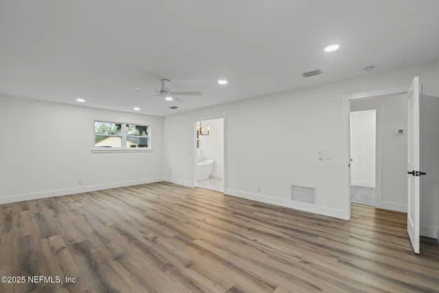 an empty room with wooden floor and windows