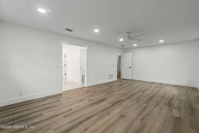 an empty room with wooden floor and natural light