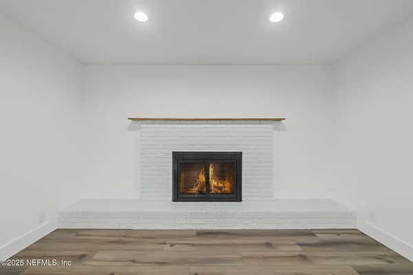 a view of an empty room with wooden floor and a fireplace