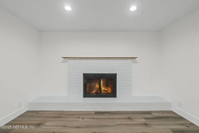 a view of an empty room with wooden floor and a fireplace